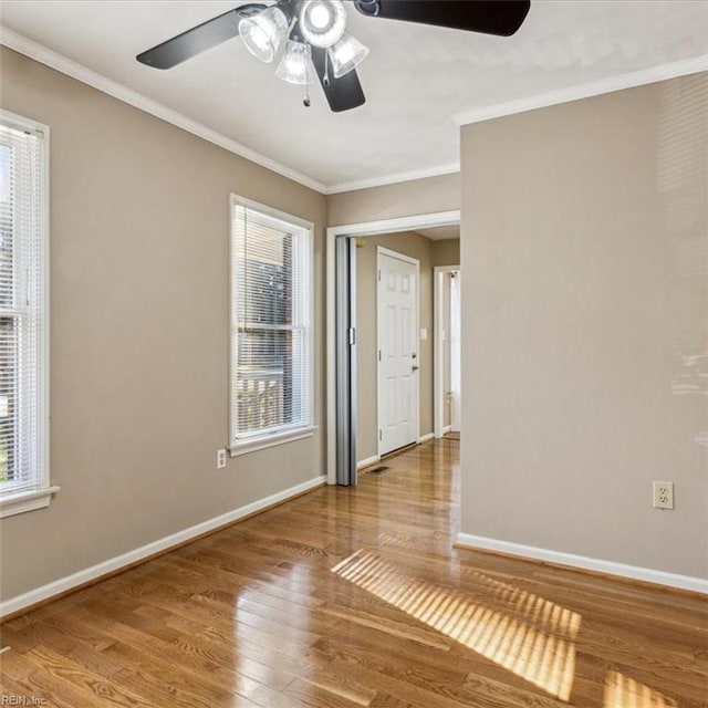 unfurnished room with plenty of natural light, ornamental molding, and wood finished floors