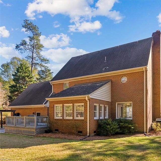 rear view of house featuring a chimney, crawl space, a deck, a yard, and brick siding