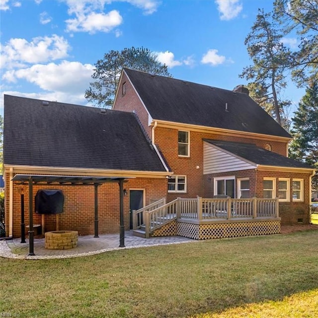 back of house with a lawn, a chimney, a wooden deck, a patio area, and brick siding