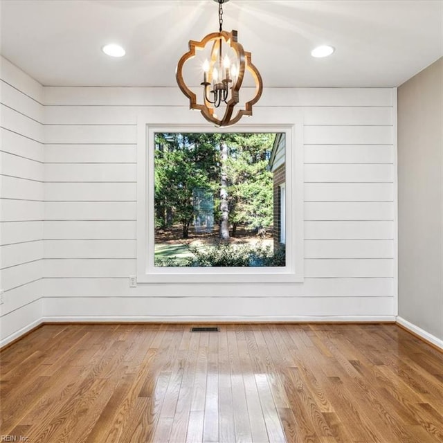 unfurnished dining area featuring recessed lighting, wood finished floors, visible vents, baseboards, and an inviting chandelier