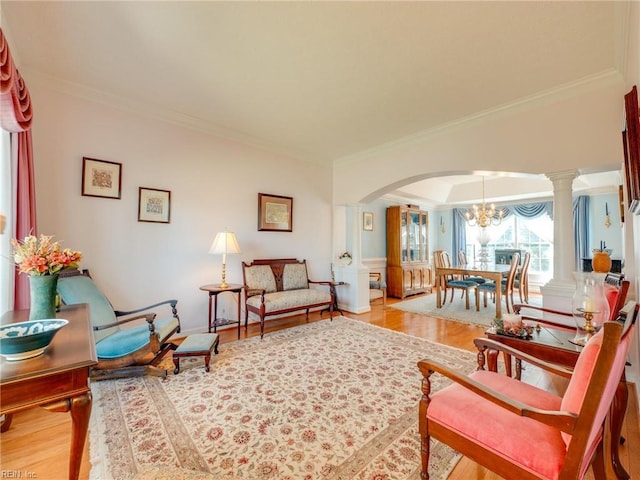 living area with light wood-style floors, arched walkways, crown molding, and decorative columns