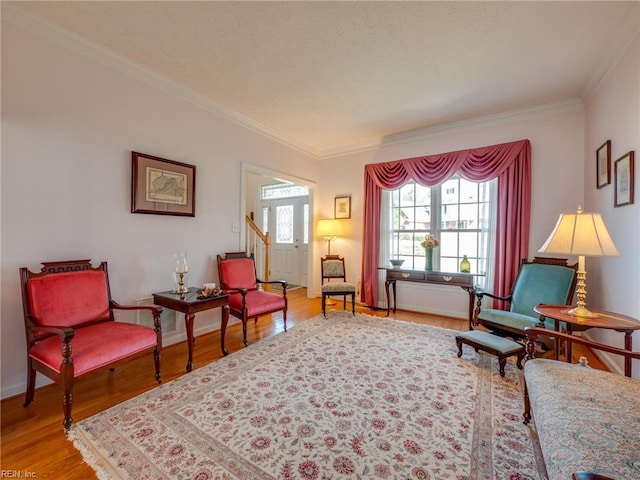 living area with baseboards, ornamental molding, and wood finished floors