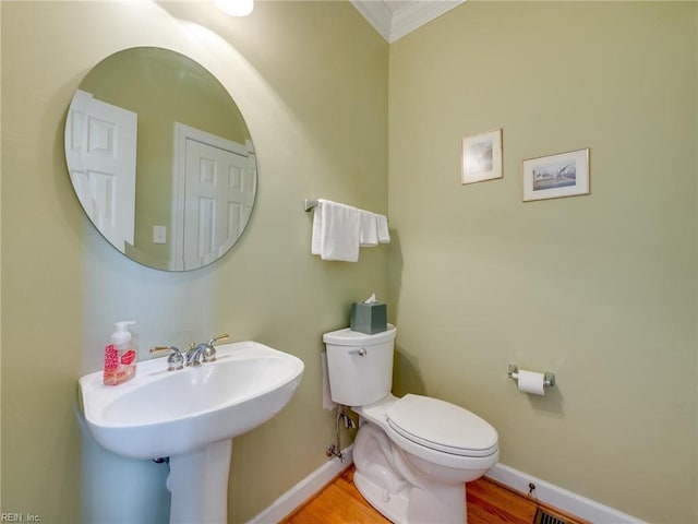 bathroom featuring baseboards, crown molding, toilet, and wood finished floors