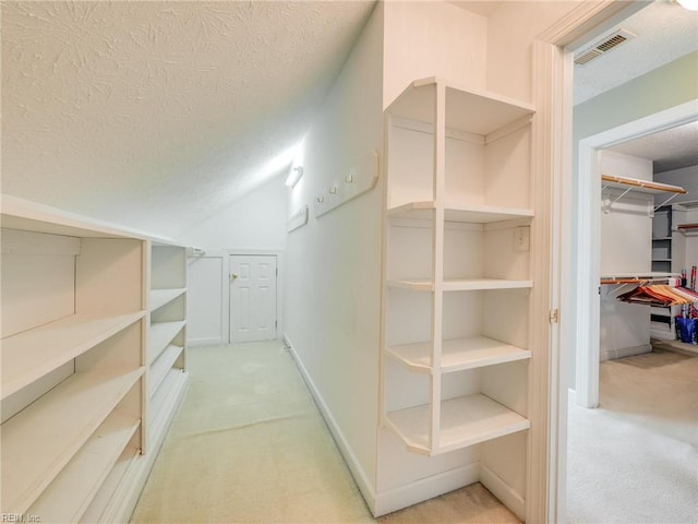 walk in closet featuring lofted ceiling, carpet flooring, and visible vents