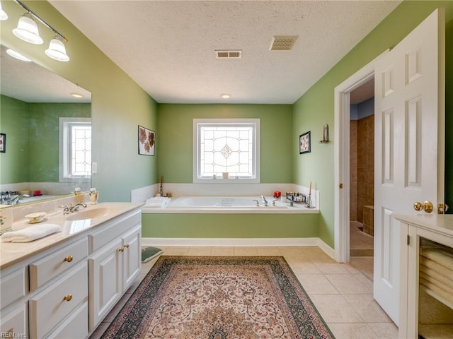 bathroom with visible vents, tile patterned floors, a textured ceiling, vanity, and a bath