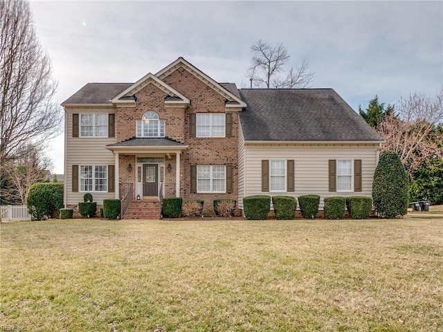 view of front facade with brick siding, fence, and a front lawn