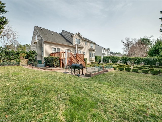 rear view of house with a garden, a lawn, stairway, fence, and a wooden deck