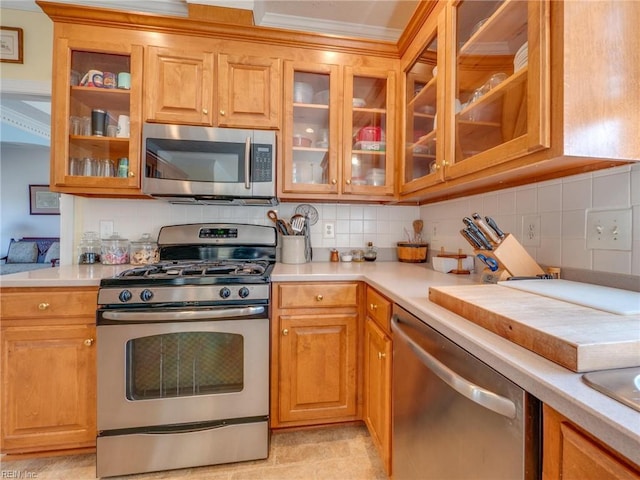 kitchen with stainless steel appliances, light countertops, tasteful backsplash, brown cabinetry, and glass insert cabinets