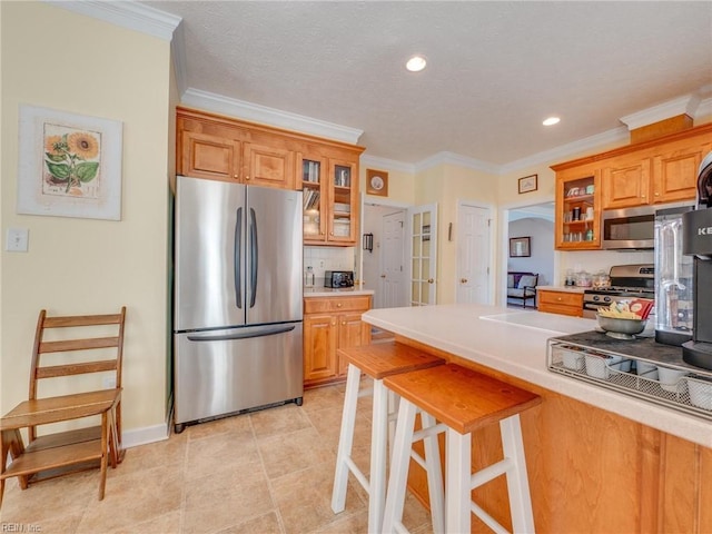 kitchen with a breakfast bar area, tasteful backsplash, appliances with stainless steel finishes, brown cabinetry, and glass insert cabinets