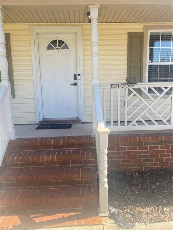 property entrance with covered porch and brick siding