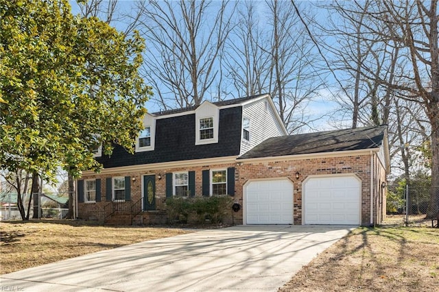 colonial inspired home featuring concrete driveway, a gambrel roof, an attached garage, fence, and brick siding