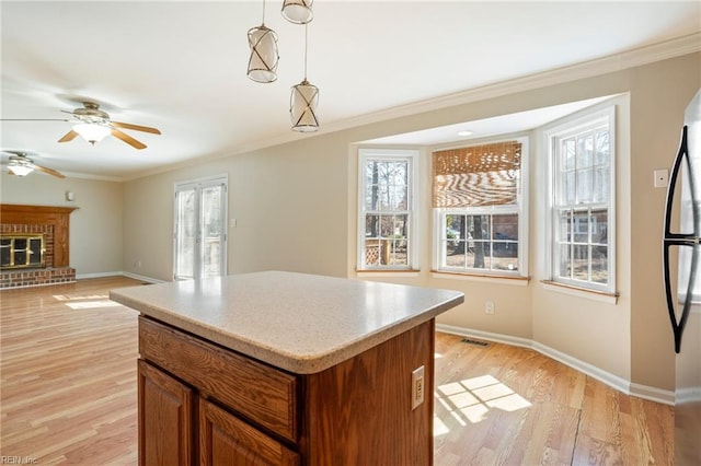 kitchen with a wealth of natural light, brown cabinets, visible vents, and light wood finished floors