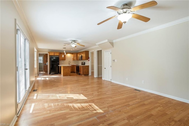 unfurnished living room featuring ornamental molding, light wood finished floors, visible vents, and baseboards