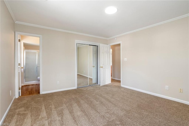 unfurnished bedroom with carpet floors, baseboards, ornamental molding, and a closet