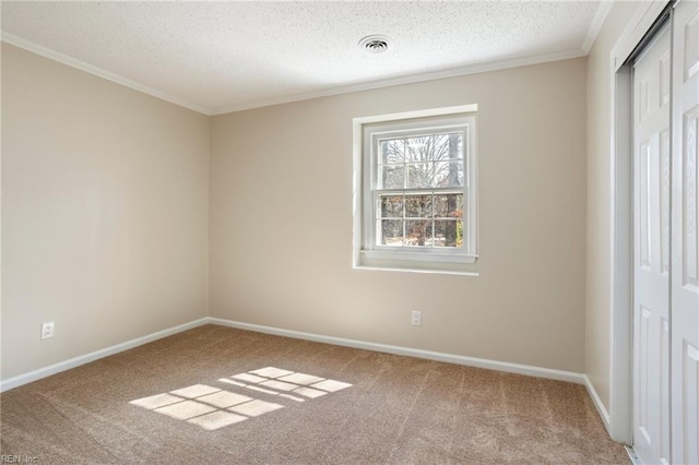 carpeted empty room with a textured ceiling, baseboards, visible vents, and crown molding