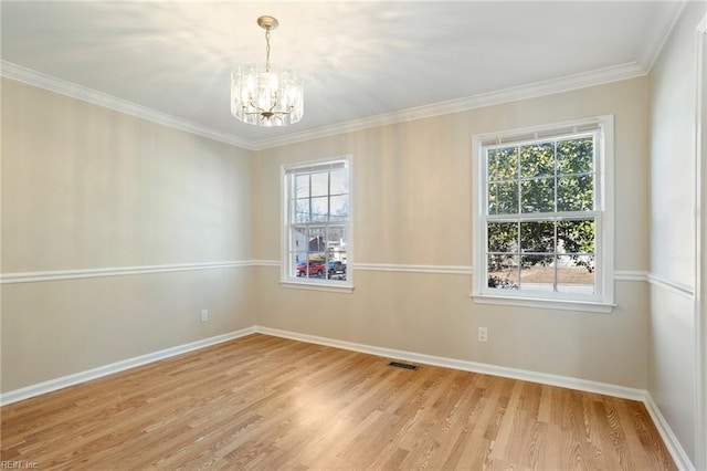 spare room featuring light wood-style floors, a healthy amount of sunlight, visible vents, and a notable chandelier