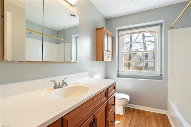 bathroom featuring toilet, wood finished floors, vanity, visible vents, and baseboards