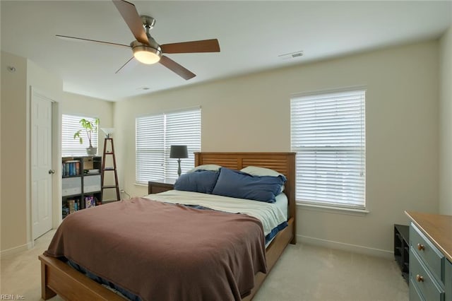 bedroom with light carpet, visible vents, baseboards, and a ceiling fan