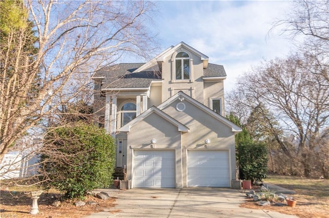 traditional-style home featuring a garage, driveway, roof with shingles, and stucco siding