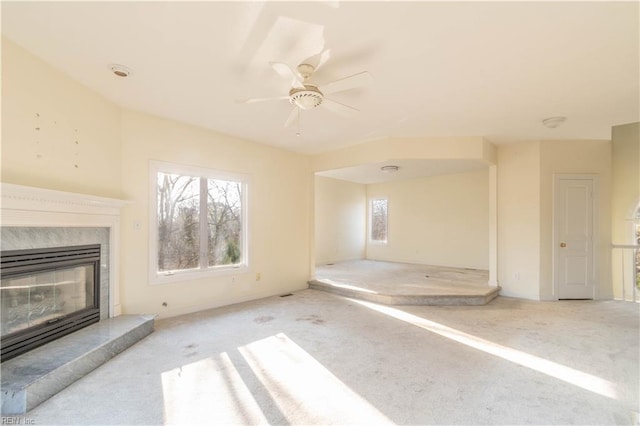 unfurnished living room featuring carpet floors, plenty of natural light, and a premium fireplace