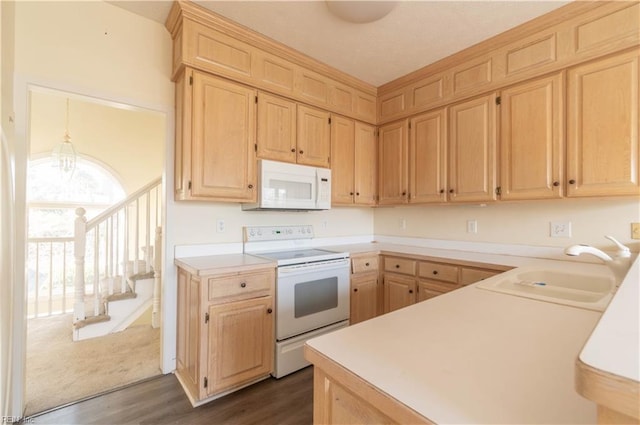 kitchen with white appliances, light countertops, a sink, and light brown cabinetry