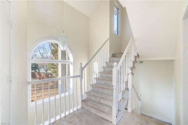 stairway featuring carpet and a high ceiling