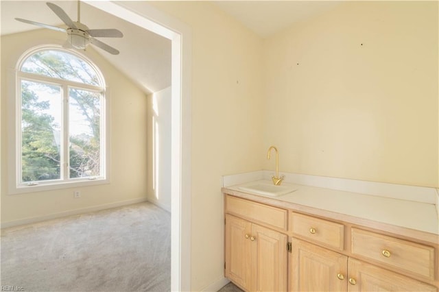 bathroom with a ceiling fan, lofted ceiling, vanity, and baseboards