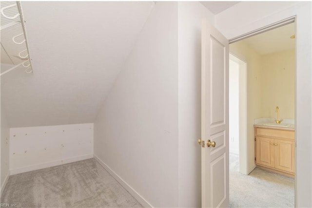 additional living space featuring vaulted ceiling, baseboards, a sink, and light colored carpet