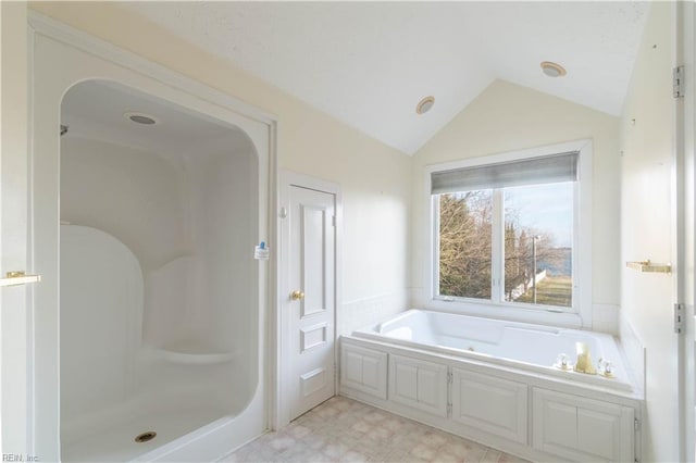 bathroom with a garden tub, vaulted ceiling, and tile patterned floors