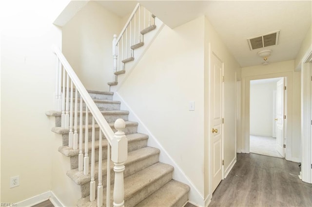 stairway with baseboards, visible vents, and wood finished floors