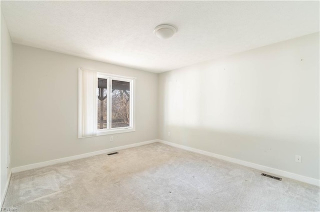 carpeted spare room featuring visible vents, a textured ceiling, and baseboards