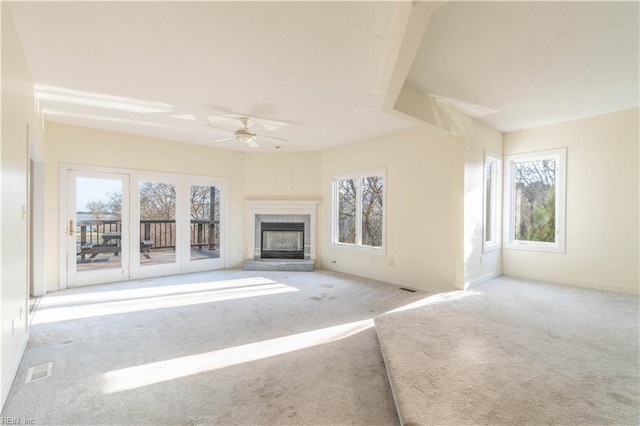 unfurnished living room featuring baseboards, visible vents, a ceiling fan, carpet floors, and a fireplace