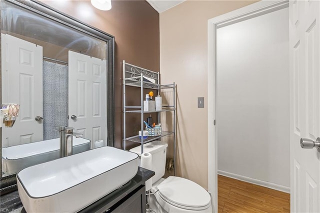 bathroom featuring vanity, wood finished floors, toilet, and baseboards