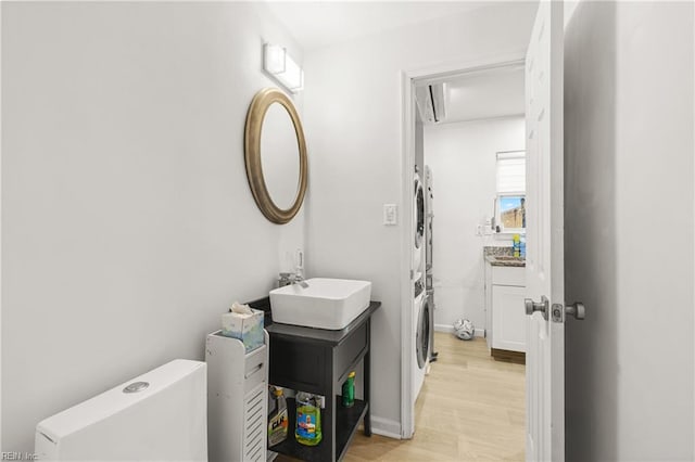 bathroom featuring stacked washer and clothes dryer, vanity, and wood finished floors