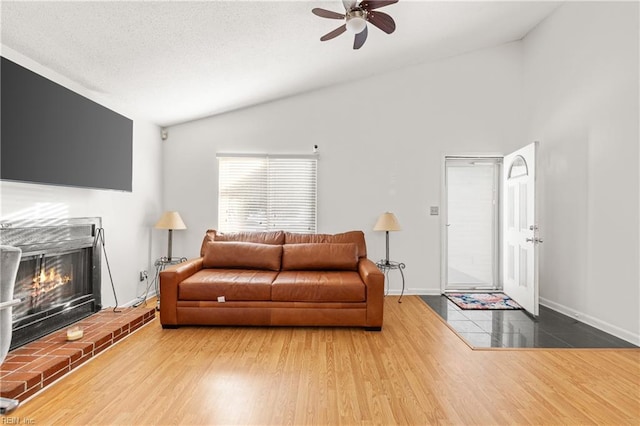 living area featuring lofted ceiling, a fireplace, wood finished floors, and baseboards