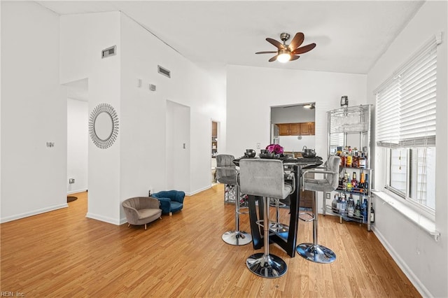 exercise room featuring lofted ceiling, light wood-style flooring, visible vents, and baseboards