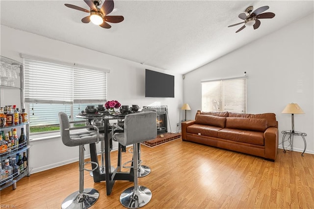 living room featuring a ceiling fan, light wood-type flooring, and vaulted ceiling