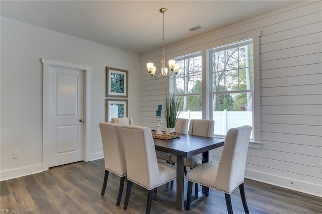 dining space with wood walls, baseboards, dark wood finished floors, and a notable chandelier