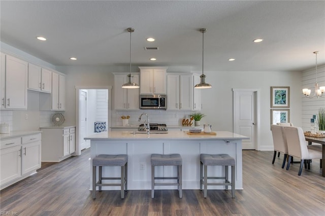 kitchen featuring a breakfast bar, stainless steel microwave, visible vents, and an inviting chandelier