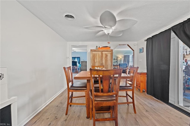 dining space with light wood finished floors, visible vents, arched walkways, and a ceiling fan