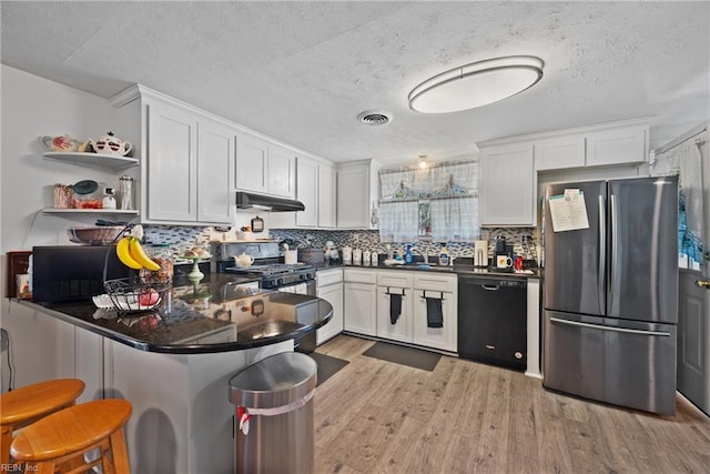 kitchen with stainless steel appliances, visible vents, light wood-style floors, a sink, and under cabinet range hood