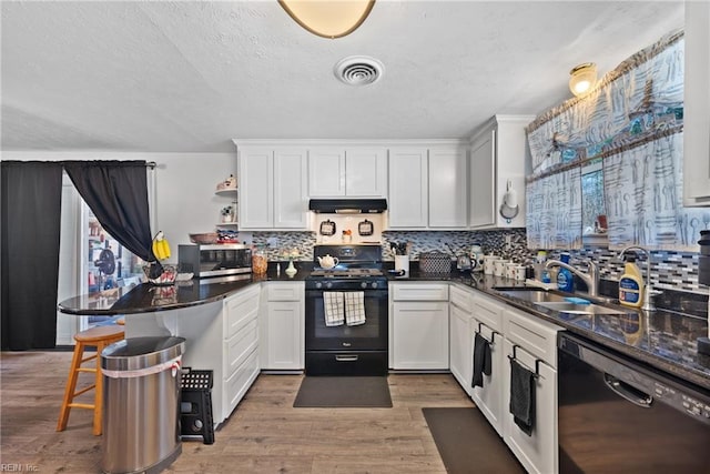 kitchen featuring visible vents, a peninsula, light wood-type flooring, black appliances, and exhaust hood