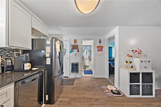 kitchen with wood finished floors, white cabinetry, heating unit, dishwasher, and tasteful backsplash