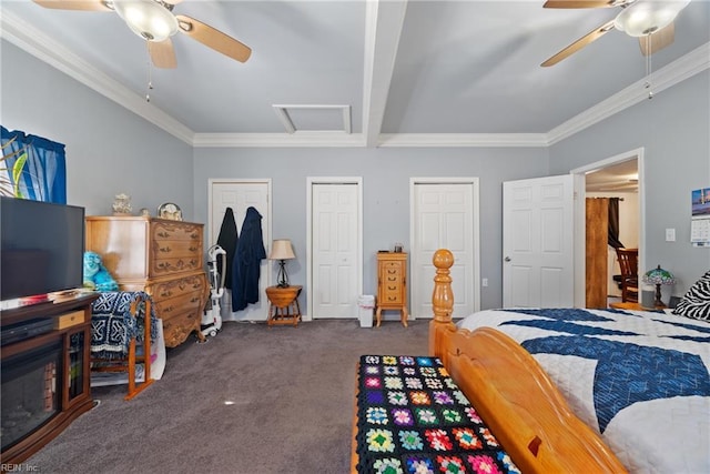 carpeted bedroom featuring attic access, crown molding, a ceiling fan, and two closets