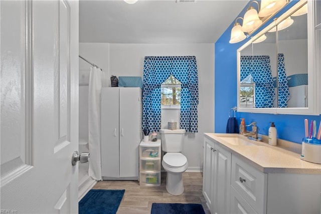 bathroom featuring toilet, wood finished floors, curtained shower, vanity, and a chandelier