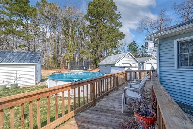 wooden terrace with a covered pool, a trampoline, a storage unit, and an outdoor structure