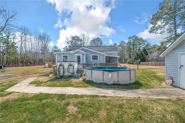 rear view of property featuring a yard and a covered pool