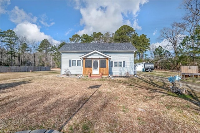 view of front of home with an outbuilding, a front lawn, a shingled roof, and fence