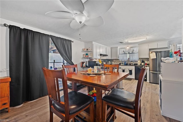 dining space with a ceiling fan and light wood-style flooring