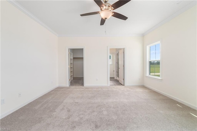 unfurnished bedroom featuring baseboards, carpet flooring, a walk in closet, and crown molding